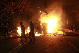 Estudantes chilenos passam em frente a cabine telefônica pegando fogo durante protesto em Santiago